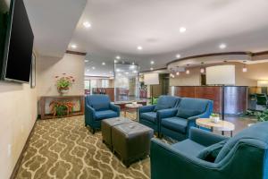 a waiting room with blue chairs and a tv at Comfort Suites in Forrest City