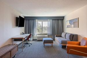 a hotel room with a couch and a desk at Sonesta Select Pleasant Hill in Pleasant Hill