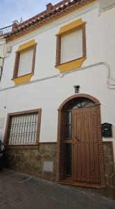 une maison avec une porte en bois et 2 fenêtres dans l'établissement Casa el albaicin, à Alhaurín el Grande