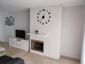 a living room with a fireplace and a clock on the wall at Sunny Guadalmina Apartment in Marbella