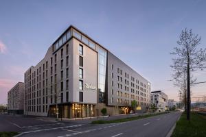 un grande edificio bianco sul lato di una strada di Radisson Hotel & Suites Zurich a Opfikon