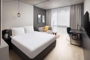 Schlafzimmer mit einem großen weißen Bett und einem Schreibtisch in der Unterkunft Radisson Hotel & Suites Zurich in Opfikon