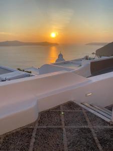 a sunset over the ocean from a white building at Elia Family Suites in Fira