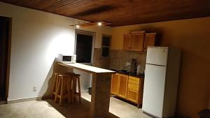 La cuisine est équipée d'un réfrigérateur blanc et de placards en bois. dans l'établissement hospedaje vicenzo, à Melo