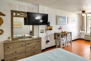 a bedroom with a dresser with a television on the wall at Ocean Jewels Resort Studio with Community Perks! in Daytona Beach