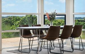 a table and chairs in a room with windows at Gorgeous Home In Or With Kitchen in Orø