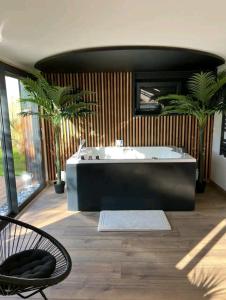 a large bathroom with a tub and a chair at ESCAPE ZEN Oasis tropicale & Spa privatif in Loon-Plage