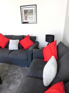 a living room with a couch and red pillows at Charming 2 bed house Perfect base for sightseeing in Johnstone