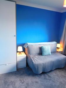 een blauwe slaapkamer met een bed met een blauwe muur bij Charming 2 bed house Perfect base for sightseeing in Johnstone