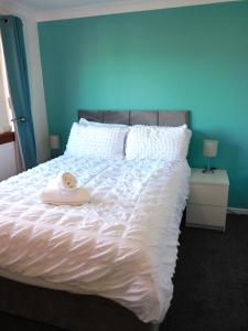 a bed with a white comforter with a towel on it at Charming 2 bed house Perfect base for sightseeing in Johnstone