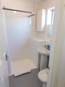 een witte badkamer met een douche en een wastafel bij Charming 2 bed house Perfect base for sightseeing in Johnstone