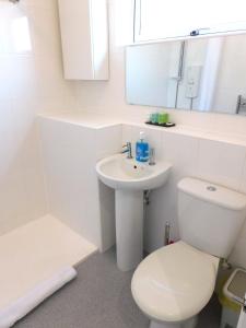 a white bathroom with a toilet and a sink at Charming 2 bed house Perfect base for sightseeing in Johnstone