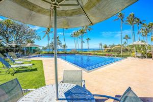 a pool with a table and chairs and an umbrella at Manualoha 608 in Koloa