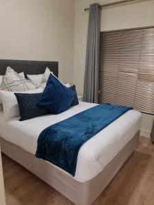 uma cama grande com almofadas azuis num quarto em Modern One Bedroom Apartment in Rivonia em Joanesburgo