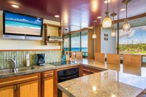 a kitchen with a sink and a tv on the wall at Kuhio Shores 207 in Koloa
