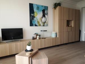a living room with a television and a wooden cabinet at Westeinders Sea View in Middelkerke