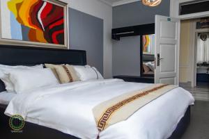 - un grand lit blanc dans une chambre avec un tableau dans l'établissement Gullivers Travel Hotel, à Apenkwa