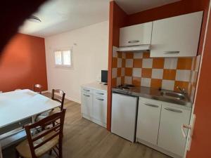 a kitchen with white cabinets and a table in a room at Les gîtes de Mazélise in Mazerolles