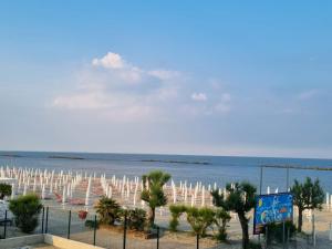 una playa con muchas sombrillas blancas y el océano en La suite (Sole), en Lido di Pomposa