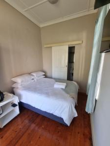 1 dormitorio con 1 cama blanca grande y suelo de madera en Capital On French Guest House, en Pietermaritzburg