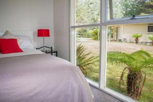 a bedroom with a bed and a large window at Russell Falls Holiday Cottages in National Park