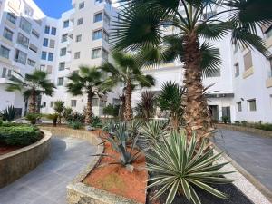 um pátio com palmeiras em frente a um edifício em Corniche Casablanca - Black New em Casablanca