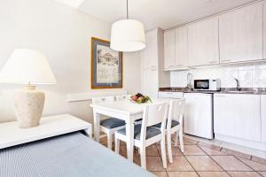 a kitchen with white cabinets and a white table and chairs at Grupotel Playa Club in Son Xoriguer