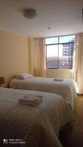 two beds in a hotel room with a window at casa hospedaje regina marie in Huaraz