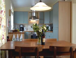 a kitchen with a wooden table with a bottle of wine at Barcloy Milk House in Kirkcudbright