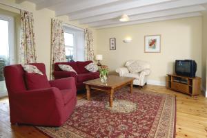 uma sala de estar com duas cadeiras vermelhas e uma mesa de centro em Barcloy Milk House em Kirkcudbright