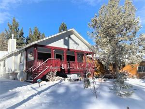 una casa con una cubierta roja en la nieve en Moose Tracks Lodge - Forest and mountain views! Smart TV with streaming app and Game Room!, en Big Bear City
