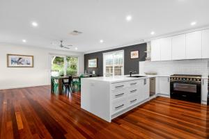 a kitchen with white cabinets and a wooden floor at Lady Nelson in Sorrento