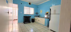 cocina con paredes azules y nevera blanca en Deck Hostel Taquaral, en Campinas