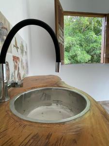 a kitchen sink with a wooden counter top and a window at Vila Marés in São Cristóvão