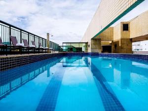 a swimming pool with blue water in front of a building at Sofisticado Flat Particular Grand Mercure in Brasilia