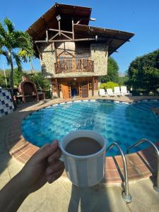 a person holding a cup of coffee in front of a swimming pool at Cabana Dubai Resorts in Santa Verónica +45 photos