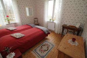 1 dormitorio con cama roja, mesa y ventanas en Villa Fridhem, Härnösand en Härnösand