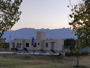 a house with a pool and chairs in front of it at Finca La Clementina in Tunuyán
