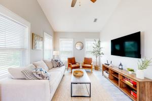 a living room with a white couch and a tv at The Emerald Cottage in Mexico Beach