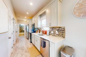 una cucina con mobili bianchi e un lavandino di The Emerald Cottage a Mexico Beach