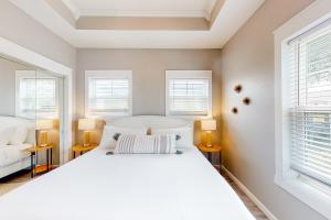 una camera da letto con un grande letto bianco e due finestre di The Emerald Cottage a Mexico Beach Altre 14 foto