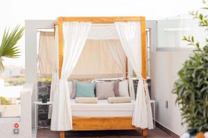 Cama en un porche con almohadas y cortinas en Arte Casa Luxury Resort, en Prasás