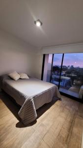 a bedroom with a large bed and a large window at Departamento moderno a una cuadra de bv. galvez in Santa Fe