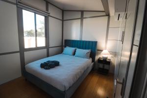 1 dormitorio con 1 cama con cabecero azul y ventana en Norwesta Lifestyle Park, en Carnarvon