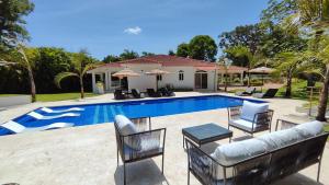 een zwembad met stoelen en een bank naast een huis bij Luxury 4-Bedroom Villa with Heated Pool in Residencial Casa Linda in Sosúa