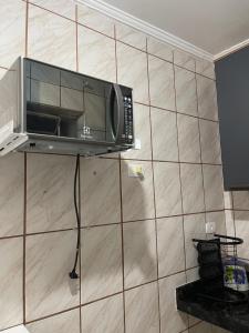 a microwave on a wall in a kitchen at Kit Net Santa Cruz in Praia Grande +5 photos