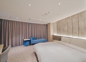 釜山にあるホテル アクア パレスの大きなベッドと青い椅子が備わるホテルルームです。