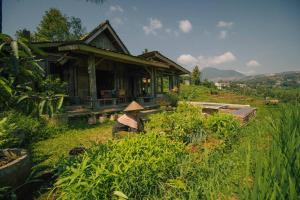 a woman sitting in the grass in front of a house at Villa Cetok Syariah - Nuansa Pedesaan in Simpen