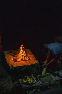 a person is standing next to a fire pit at Villa Cetok Syariah - Nuansa Pedesaan in Simpen