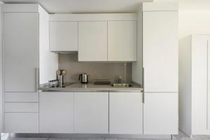 eine weiße Küche mit weißen Schränken und einem Waschbecken in der Unterkunft Cozy Bright Studio W Parking, Poolviews! #237 in Istanbul